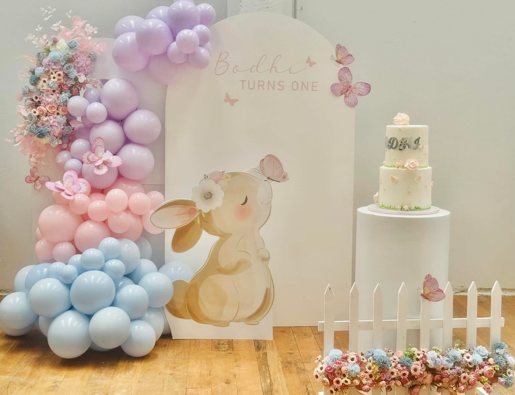 Pastel bunny themed first birthday backdrop with florals and a tiered cake