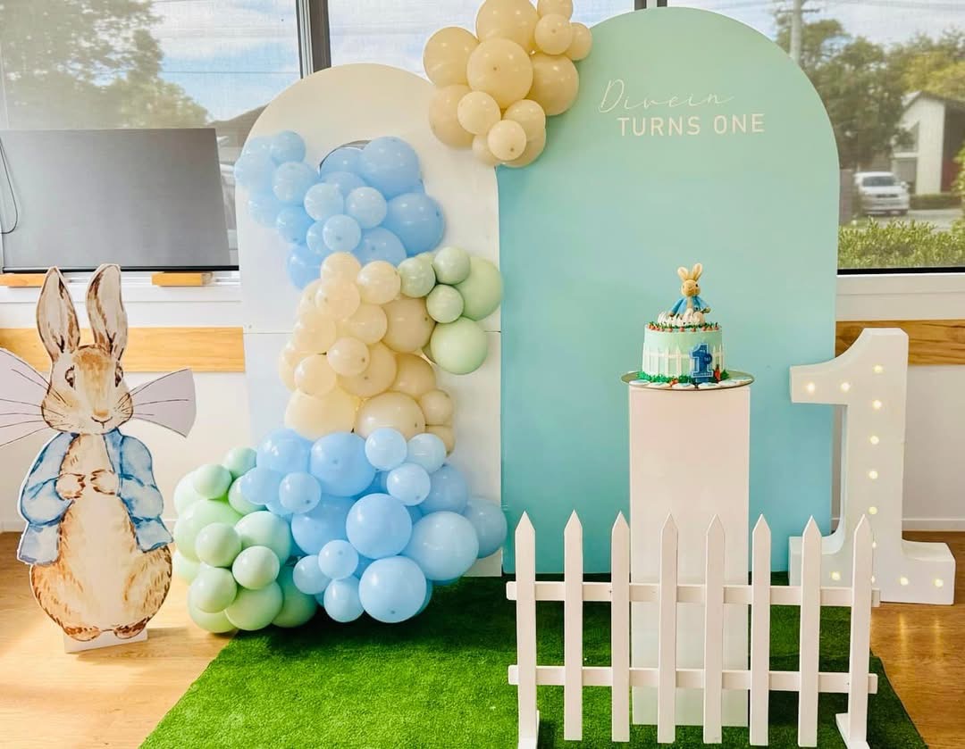 Peter Rabbit themed first birthday balloon arch in blue and sage